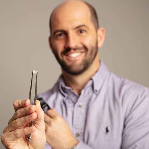 Joseph Dolginow at Dolgins Jewelry Store showing off a round brilliant diamond in tweezers.