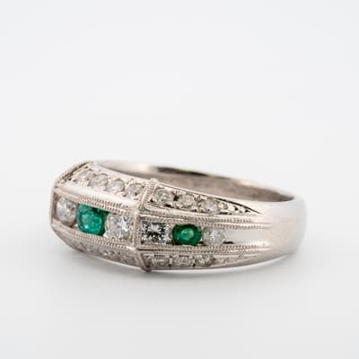 Side image of platinum ring with round emeralds and diamonds showing the milgrain edge.