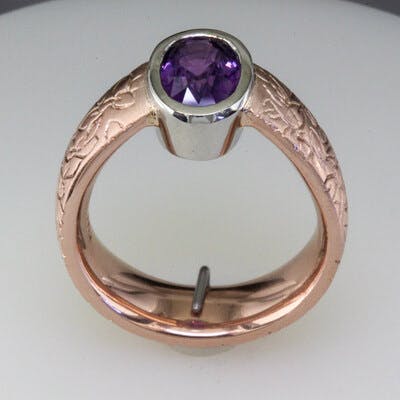Side view of oval purple sapphire in rose gold ring