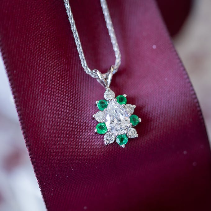 Diamond Pear pendant with halo of round diamonds and emeralds