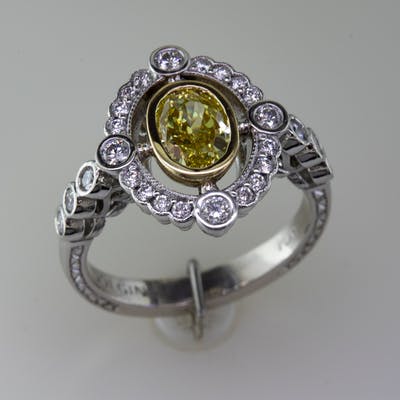 Angled view of platinum fancy yellow diamond halo ring
