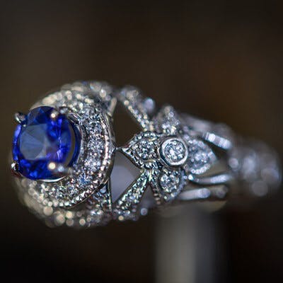 View of the ring shoulder showing the milgrain and diamonds and round sapphire