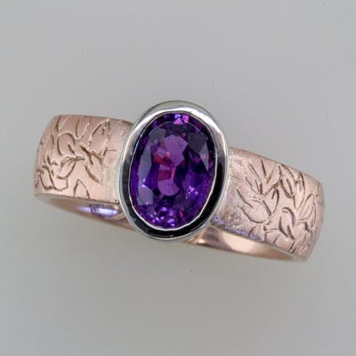 Top view of oval purple sapphire in rose gold ring