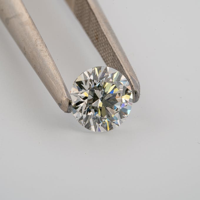 Tweezers holding stunning GIA 1 carat round diamond